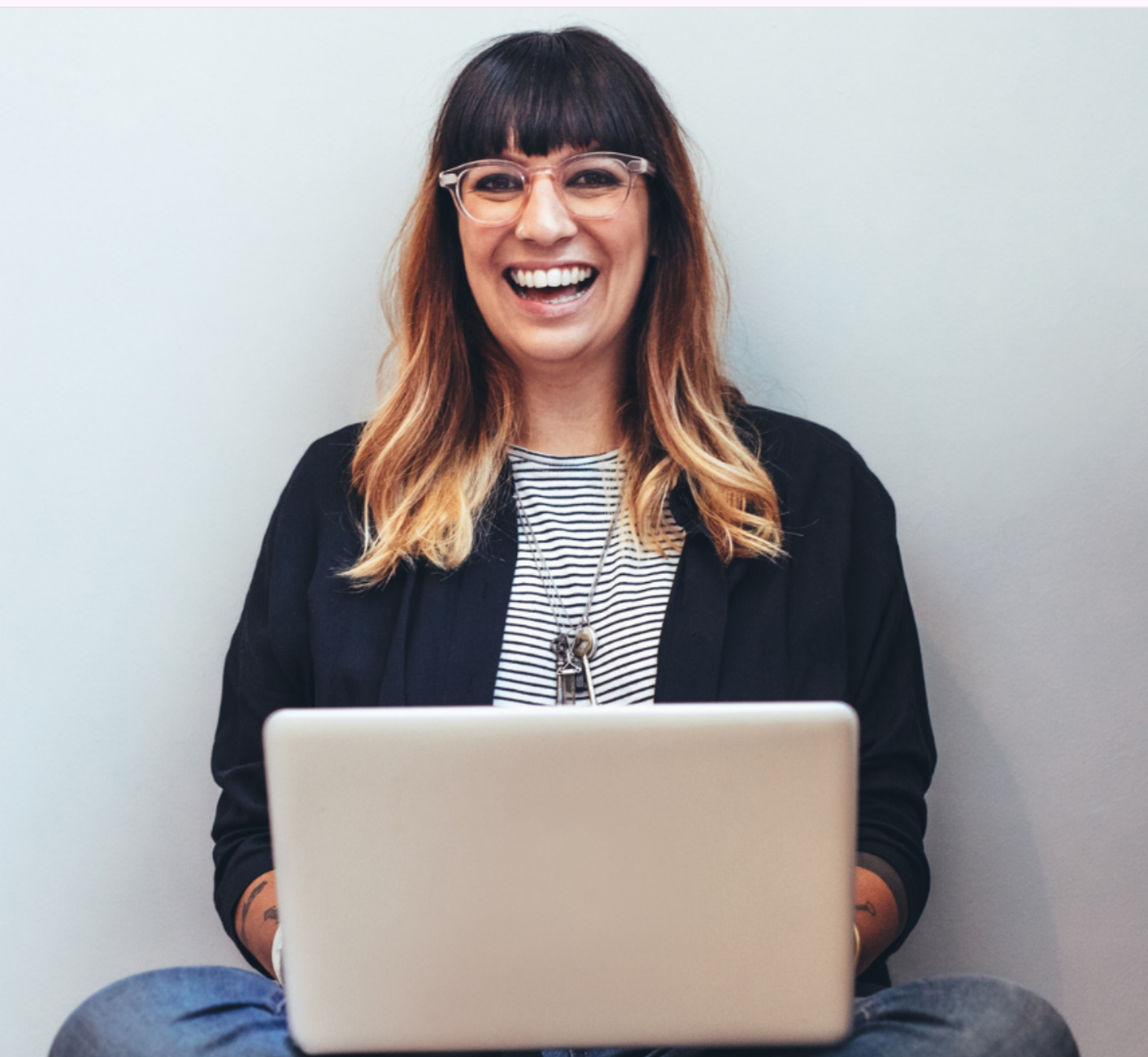 Smiling woman entrepreneur with laptop, representing our mission